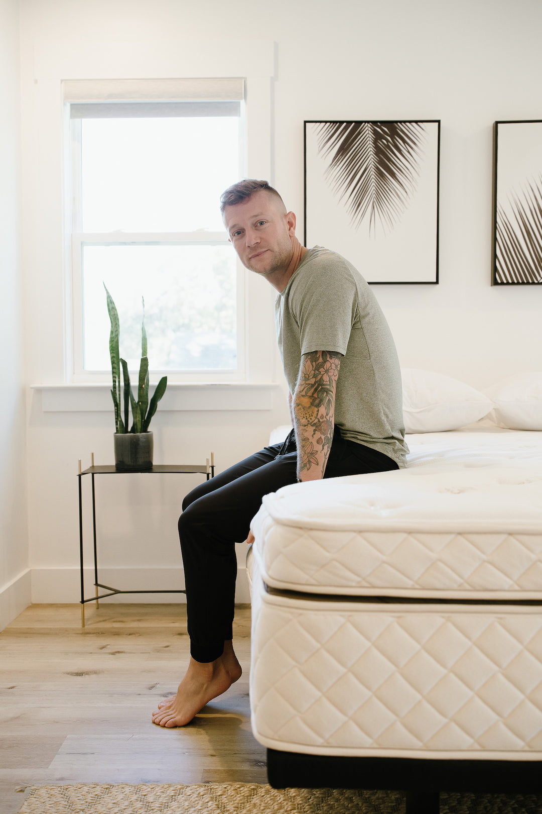 An image of the DUO Mattress with a man sitting on the edge showing its sturdy edge support and its unique 2-piece mattress design.