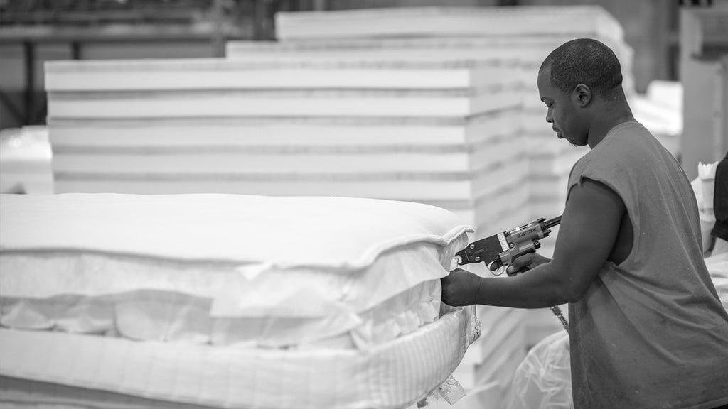 man assembling a mattress at a factory