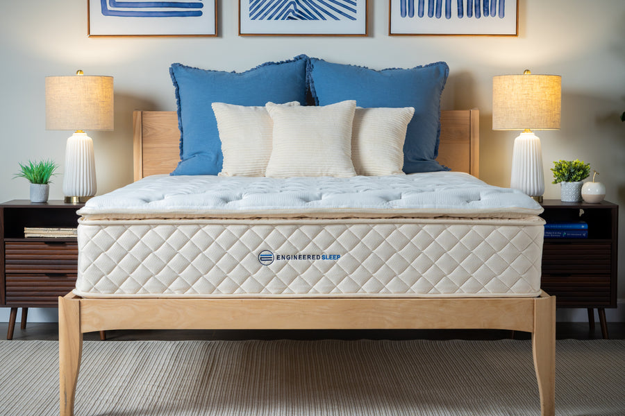 Duo Mattress on a wooden bed frame with blue and white pillows in a bedroom setting.
