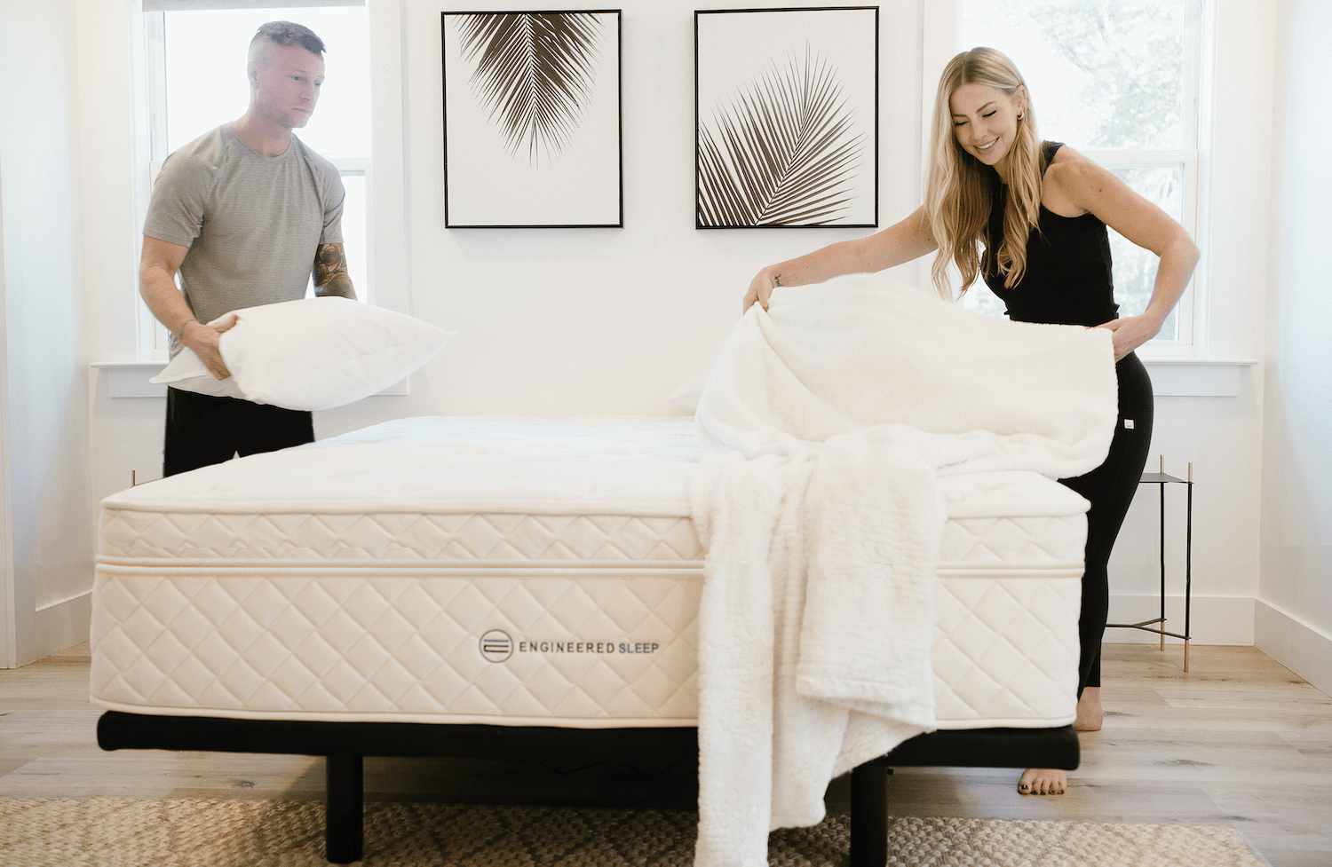 couple making the bed with a duo memory foam engineered sleep mattress