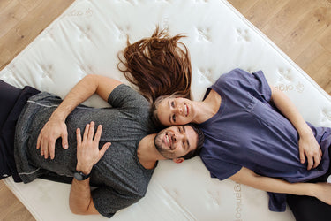 a smiling couple laying on the duo mattress by engineered sleep