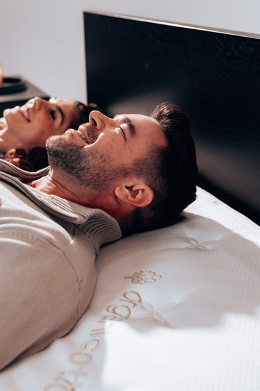 a man and woman smiling laying on the duo latex mattress