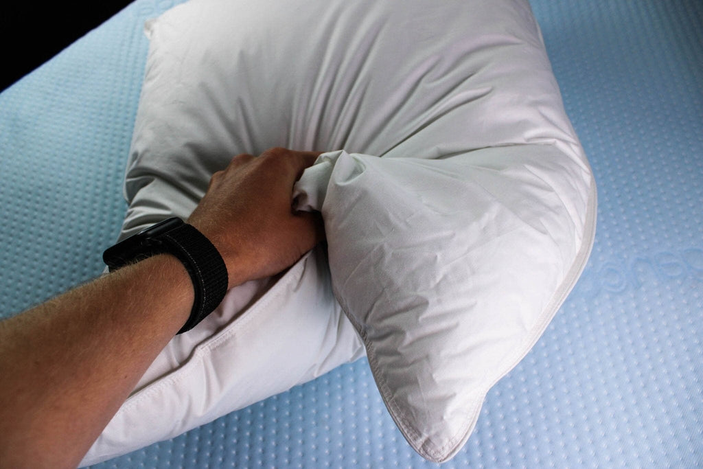 down bed pillow with hand showing how soft it is